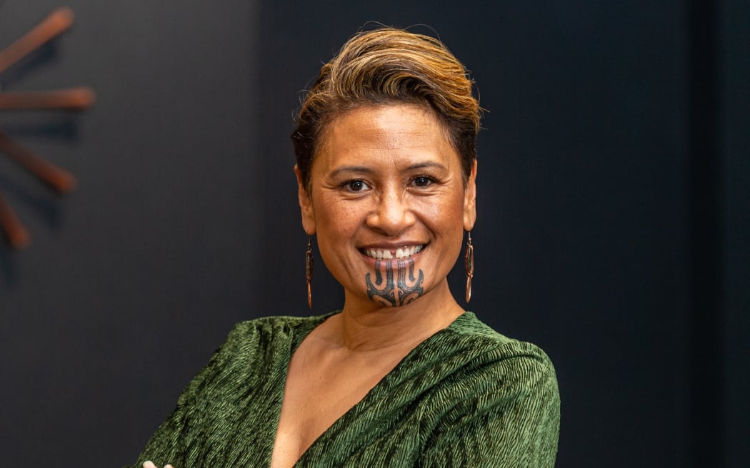 Rachel Petero wears a green dress and looks directly at the camera.
