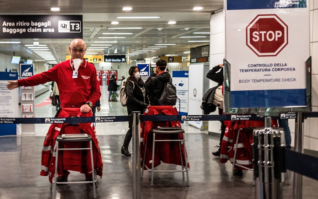 An airport staff directs passengers exiting an airplane that landed at Rome's Fiumicino airport from Paris on March 7, 2020 as part of body temperature screening procedures to prevent the spread of the new coronavirus.