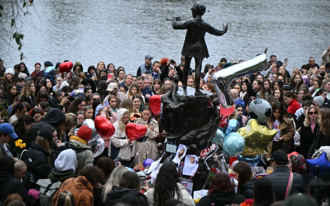 Fans of former One Direction singer Liam Payne gather with balloons and flowers beside the Peter Pan statue in Kensington Gardens, adjacent to Hyde Park for a memorial following the singer's death earlier in the week, in London on October 20, 2024. - Payne, fell from a third-floor hotel balcony in Buenos Aires, the  Argentinian capital on Wednesday. While the exact circumstances of the fall are unclear, police said they responded to a report of "an aggressive man who may be under the influence of drugs or alcohol". (Photo by JUSTIN TALLIS / AFP)