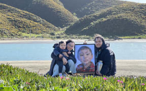 Neil and Abegail, along with their younger son, Sedric, hold a portrait of their older son, Sebby Chua, who died at Wellington Hospital in September, 2022.