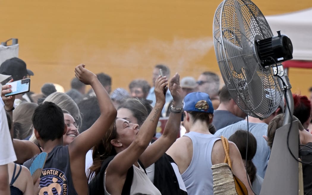 Tourists cool off by a water spraying ventilator before entering the Colosseum monument on July 24, 2023 in Rome during a heatwave.