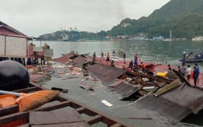 People stand on the roofing of collapsed shops in the port after a 5.2-magnitude earthquake in Jayapura.