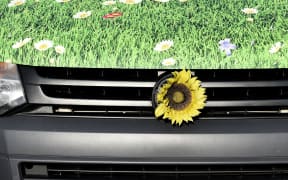 A sunflower decorates a "green" VW electric car at a service station in Berlin.