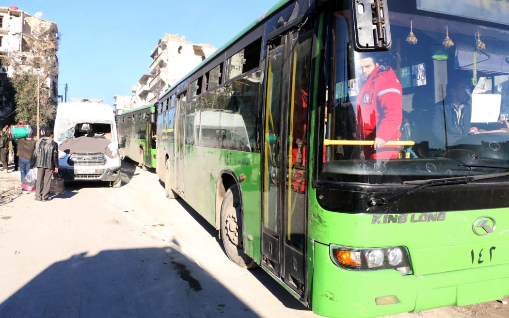 A convoy including buses and ambulances, wait at a crossing point at Amiriyah District of Aleppo.