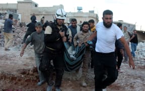 Civil defence members and civilians carry a body from debris airstrikes over residential area in Batebo district of Aleppo.