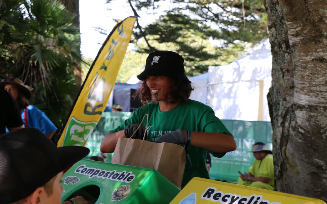 One of many helping hands tasked with rubbish duty at Te Matatini helps whānau place their rubbish in the correct bin.