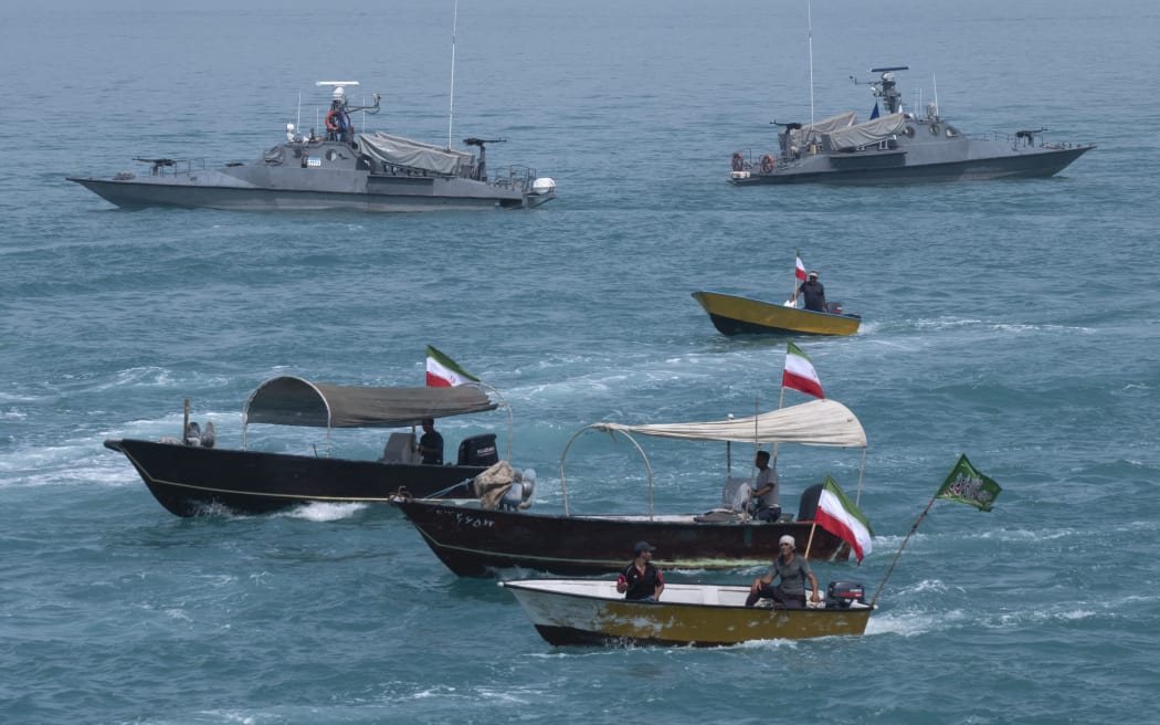 Two Islamic Revolutionary Guard Corps (IRGC) Navy warships and Basij paramilitary force speed boats are sailing along the Persian Gulf during the IRGC marine parade, which is commemorating the Persian Gulf National Day, near the Bushehr nuclear power plant in the seaport city of Bushehr, Bushehr province, in the south of Iran, on April 29, 2024. The Persian Gulf National Day, celebrated on the 10th of Ordibehesht in the Iranian calendar, usually falls in late April or early May and commemorates the expulsion of the Portuguese from the Strait of Hormuz and the Persian Gulf in 1622 by the Safavid forces led by Imam Quli Khan under the command of Shah Abbas I. (Photo by Morteza Nikoubazl/NurPhoto) (Photo by Morteza Nikoubazl / NurPhoto via AFP)