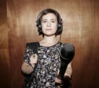 A portrait of Bang! presenter Melody Thomas, thrusting a microphone towards the camera.