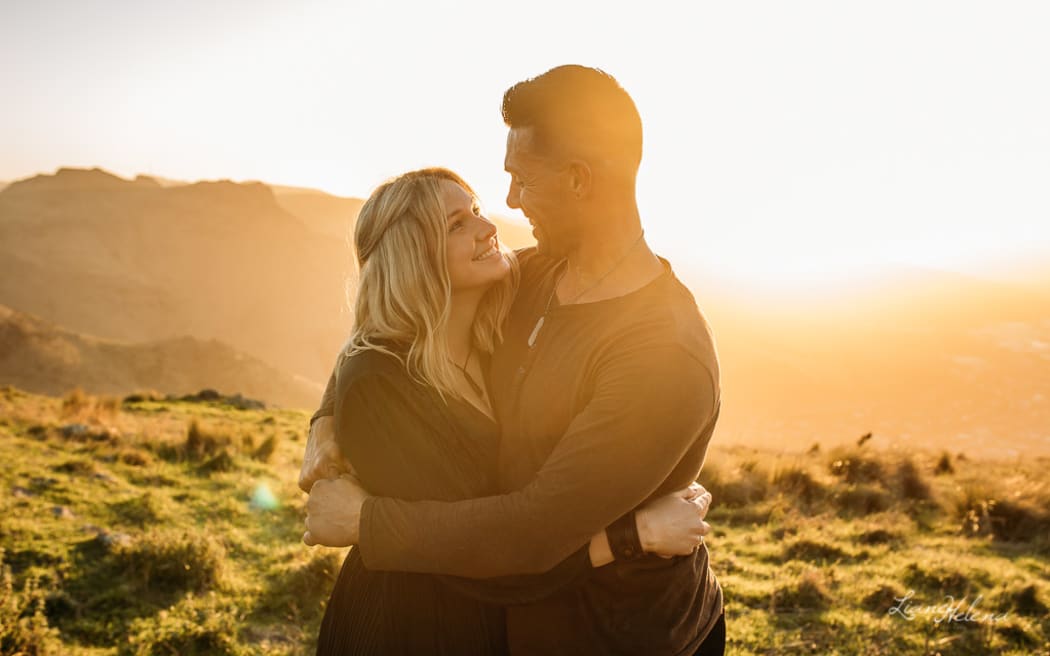 Samantha McConnell and her husband stare into each other's eyes in a field with the sun behind them.
