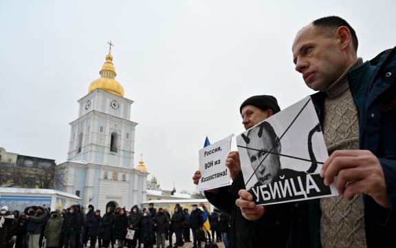People hold placards depicting Russian president Vladimir Putin signed "Killer" and another one reading "Russia, go out from Kazakhstan!" during an action dubbed #SayNOtoPutin in Kyiv.