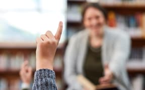 Pick me, I know the answer teacher. elementary school kids hand raised in the library