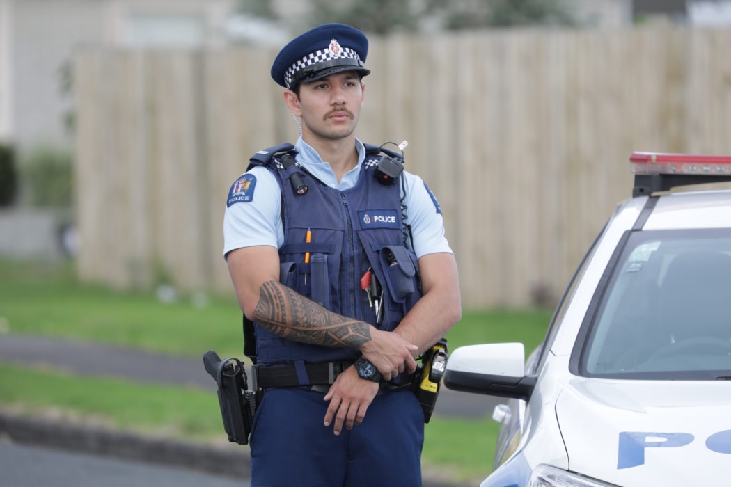 A police officer standing guard at a cordon in Papatoetoe after a man was shot by police.