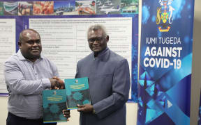 Prime Minister Manasseh Sogavare (right) hands the Economic Stimulus Package document over to the Minister of Finance and Treasury, Harry Kuma.