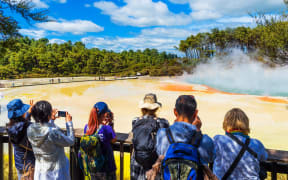 A group of people visiting the geothermal pools in Wai-O-Tapu park.