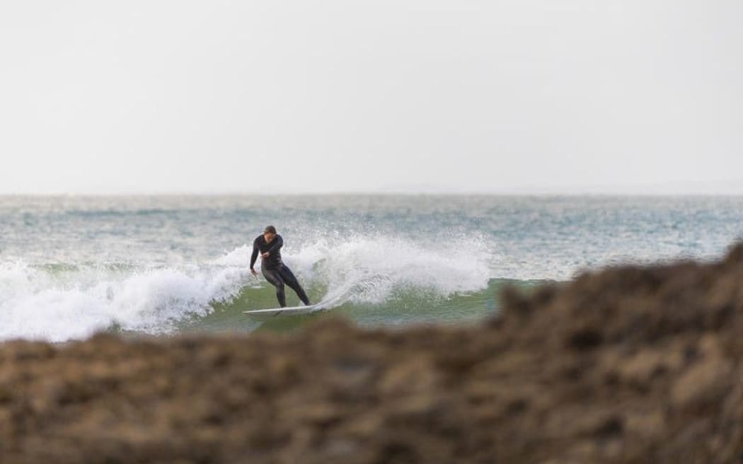 A surfer catches a wave at Ahipara, from the book Surf Dreams. ONLY USE IF RELATED TO BOOK.