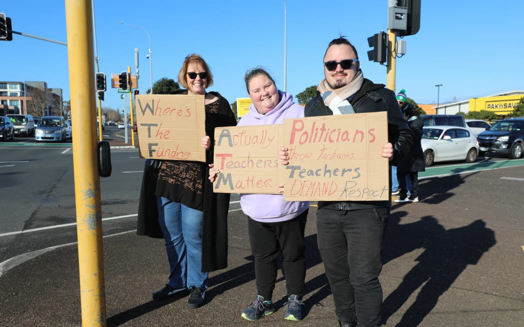 A family of secondary school teachers stand at the intersection of Universal Drive and Lincoln Road in Henderson. They are striking after the government offered them a 1% payrise.