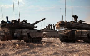 Israeli troops and tanks gather in a field near the kibbutz Beeri in southern Israel on October 14, 2023, close to the spot where 270 revellers were gunned down or burnt in their cars by Hamas gunmen at the Supernova music festival in the Negev desert on October 7. Hamas launched a large-scale attack on Israel on October 7 which killed at least 1300 people, sparking a retaliatory bombing campaign that has killed more than 1900 in the Gaza Strip ahead of a potential Israeli ground invasion of the territory. (Photo by Thomas COEX / AFP)