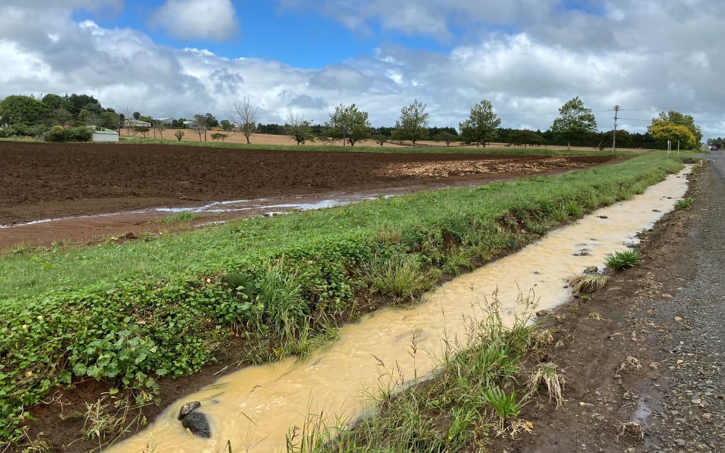 Water still flows next to a field completely washed out of its onions.