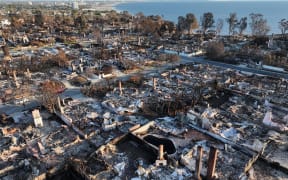 An aerial view of homes destroyed in the Palisades Fire with the Pacific Ocean in the distance on January 27, 2025 in Pacific Palisades, California. Rain and snowfall across Southern California has temporarily tamed the threat of major wildfires in the region. Multiple wildfires fueled by intense Santa Ana Winds burned across Los Angeles County leaving at least 28 dead with over 180,000 people having been under evacuation orders. Over 12,000 structures, many of them homes and businesses, burned in the Palisades and Eaton Fires.