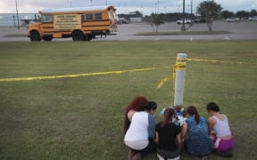 Mourners say a prayer after leaving flowers in front of Santa Fe High School on May 19, 2018 in Santa Fe, Texas.