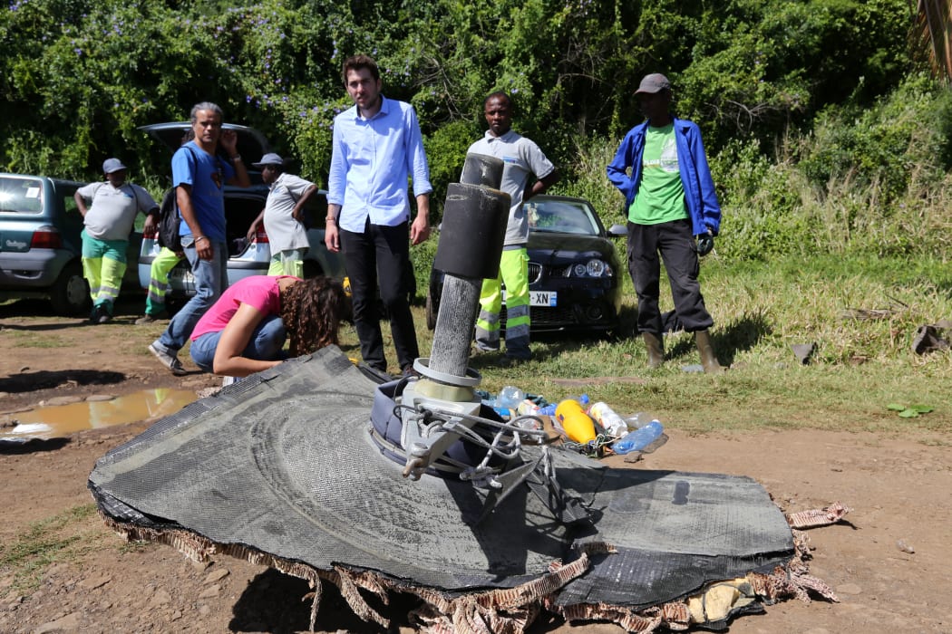 Local ecological association members and volunteers stand behind debris found on August 11, 2015 in the eastern part of Sainte-Suzanne, on France's Reunion Island in the Indian Ocean,