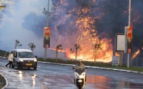 Israelis drive past a fire in the northern Israeli port city of Haifa.