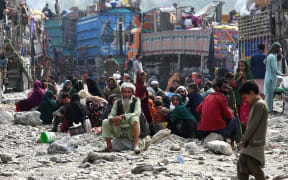 Afghan refugees rest near trucks upon their arrival from Pakistan at the Afghanistan-Pakistan Torkham border in Nangarhar province on November 1, 2023. Islamabad issued an ultimatum in early October to 1.7 million Afghans it says were living illegally in Pakistan: leave by November 1 or face arrest and expulsion. (Photo by Wakil KOHSAR / AFP)