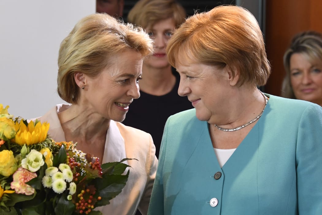 German Defence Minister Ursula von der Leyen talks to German Chancellor Angela Merkel after receiving flowers as she leaves the weekly cabinet meeting on 17 July, 2019 in Berlin.