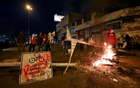 Demonstrators block a street with a barricade in Cali, Colombia during a protest against a tax reform bill.