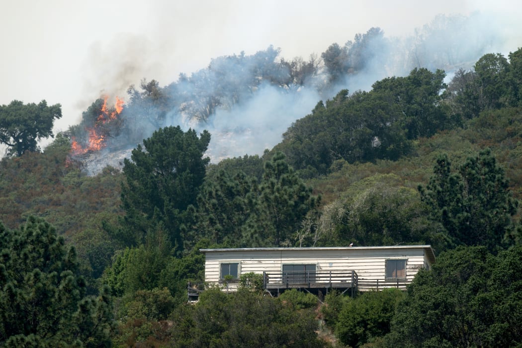 Flames from the Soberanes Fire burns behind a home in Carmel-by-the-Sea, California on 24 July.