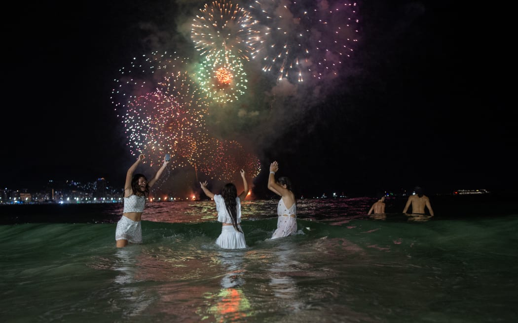 People celebrate as they watch the traditional New Year's fireworks at Copacabana Beach in Rio de Janeiro, Brazil, on 1 January, 2024.