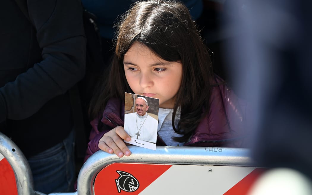 ROME, ITALY - APRIL 26: A young faithful holds a photo of late Pope Francis during the funeral procession arrives at the Basilica of Santa Maria Maggiore during the funeral of Pope Francis on April 26, 2025 in Rome, Italy. Pope Francis died on April 21st at the age of 88. Born in Argentina as Jorge Mario Bergoglio, he was the first Latin American and the first Jesuit to become Pope when elected in 2013. Taking the name Francis after St Francis of Assisi, he promoted a more humble version of the papacy than many of his predecessors. He will be buried outside of the Vatican in a simple wooden coffin at the Basilica Santa Maria Maggiore.  (Photo by Alexi J. Rosenfeld/Getty Images)