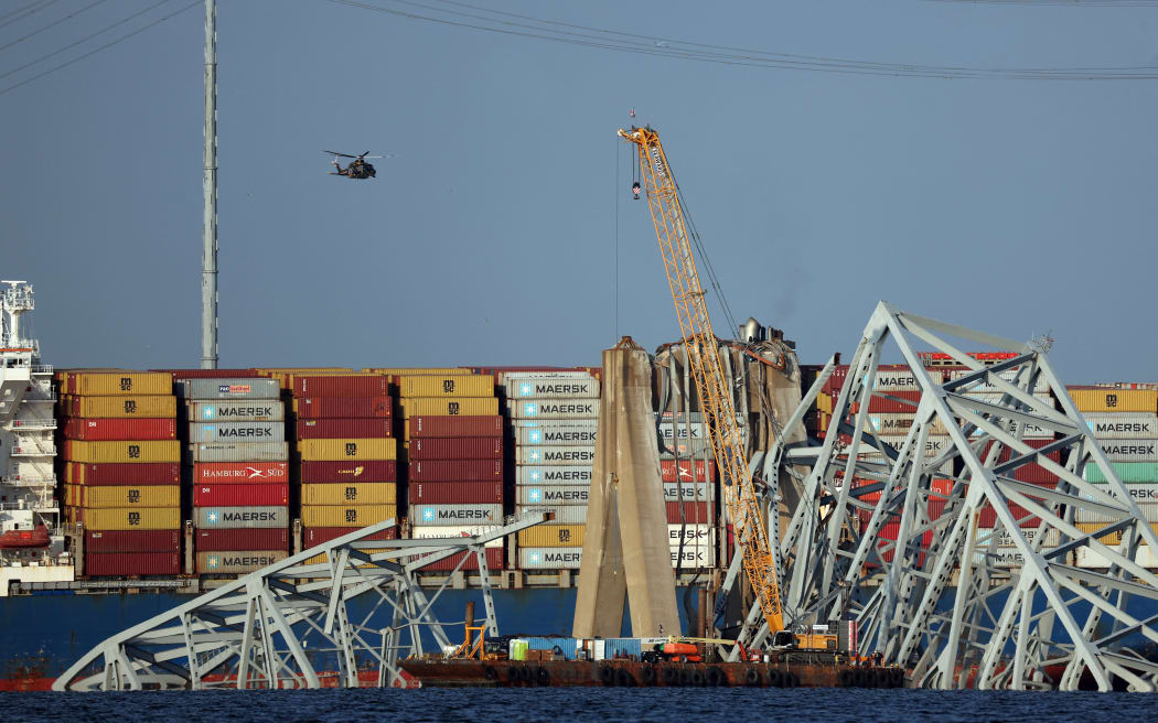 BALTIMORE, MARYLAND - MARCH 29: A crane works on clearing debris from the Francis Scott Key Bridge on March 29, 2024 in Baltimore, Maryland. The bridge collapsed on Tuesday at 1:30AM, after being struck by the massive cargo ship Dali. Two members of a road repair crew were pulled from the Patapsco River immediately after the collision, while two other bodies were pulled from the water on Wednesday and four people remain missing and are presumed dead after the Coast Guard called off rescue efforts. The accident has temporarily closed the Port of Baltimore, one of the largest and busiest on the East Coast of the U.S.   Kevin Dietsch/Getty Images/AFP (Photo by Kevin Dietsch / GETTY IMAGES NORTH AMERICA / Getty Images via AFP)