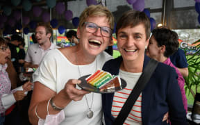 A couple poses with a wedding cake's slice during an event following a nationwide referendum on same-sex marriage, in Swiss capital Bern on September 26, 2021.
