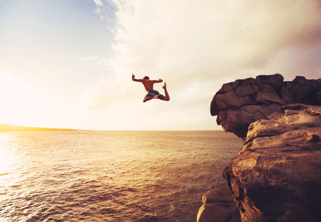48837469 - cliff jumping into the ocean at sunset, outdoor adventure lifestyle