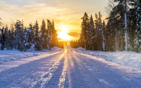 Sunset over an empty snowy road, Lapland, Finland, Europe (Photo by Roberto Moiola / Robert Harding RF / robertharding via AFP)