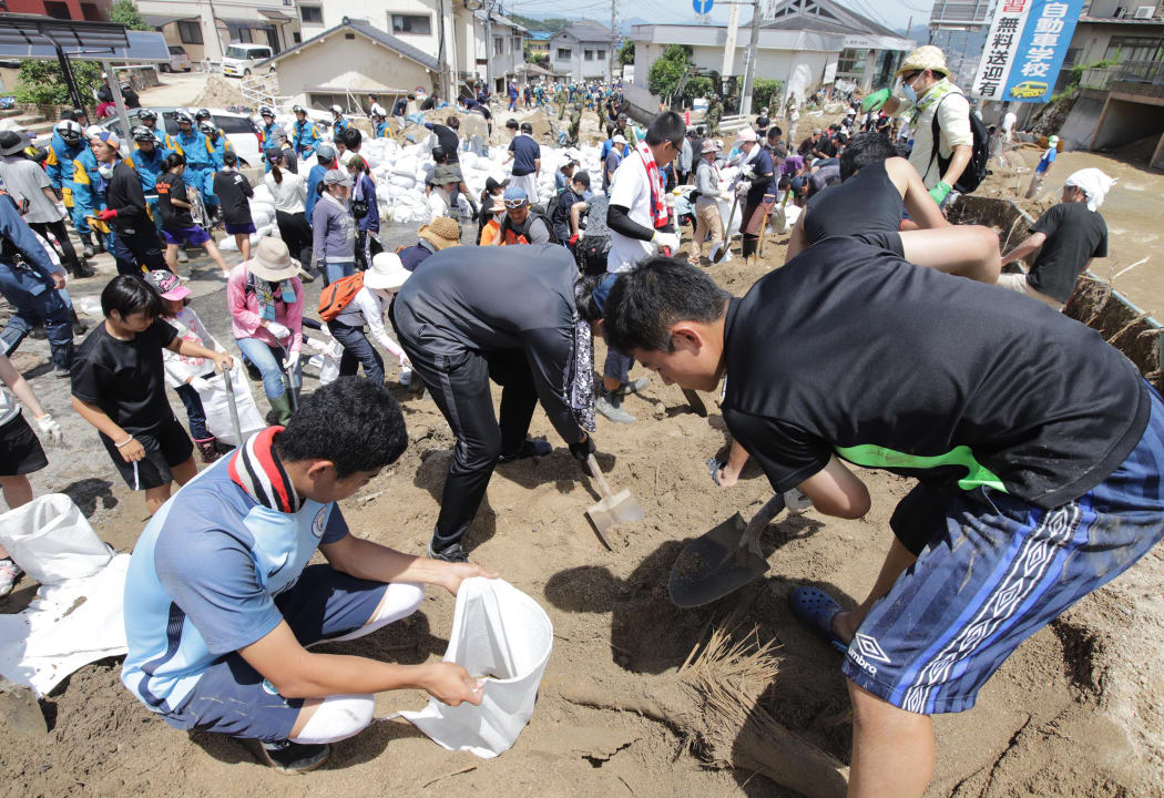 Volunteers and firefighters conduct a search operation for a rising number of missing people in Hiroshima City after torrential rain brought on by an active seasonal rainy front.