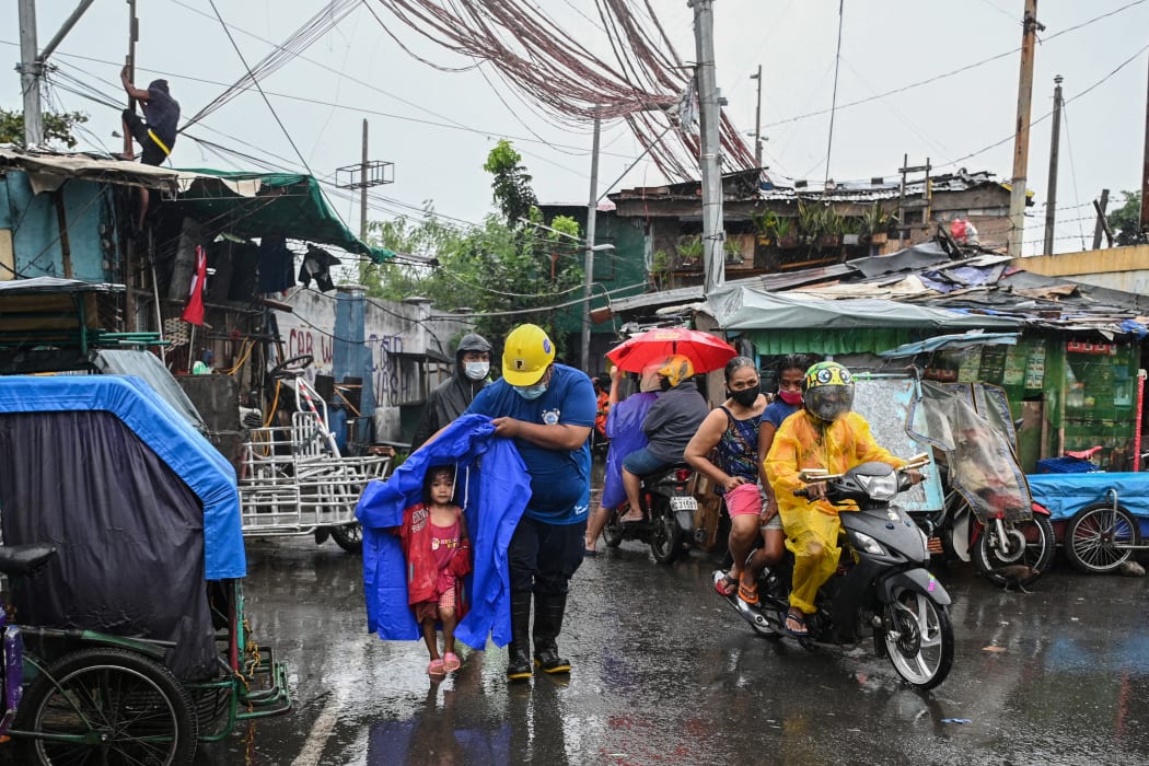 A rescue worker escorts a child to a waiting vehicle during an evacuation of informal settlers living along coastal areas in Manila
