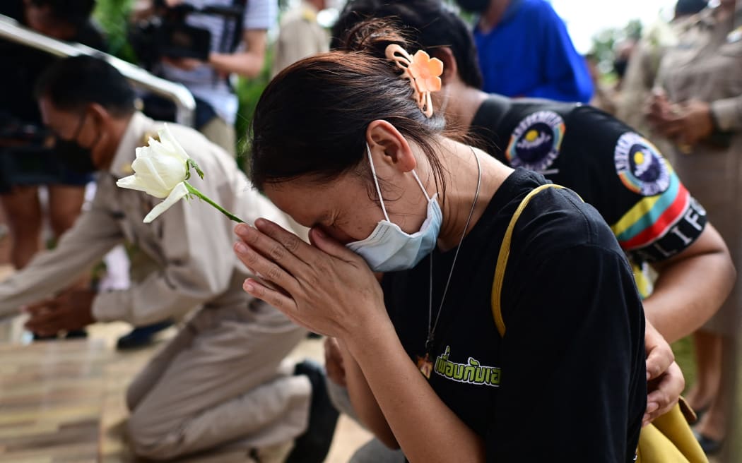A woman offers a white rose on the steps of the nursery where a former police officer killed at least 34 people, in Thailand's northeastern Nong Bua Lamphu province.