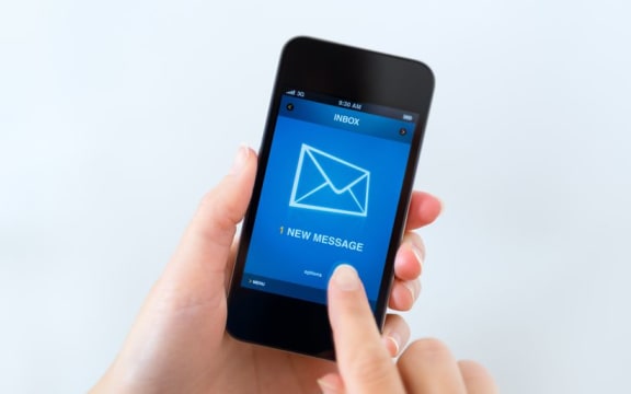 Woman holding phone showing email inbox.