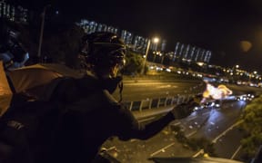 A protester throws a molotov cocktail to stop vehicles from passing through their road block beneath a bridge at the Chinese University of Hong Kong (CUHK) on November 15, 2019.