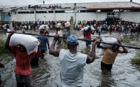 People looting sacks of Chinese rice printed "China Aid" from a warehouse surrounded in Beira, Mozambique.