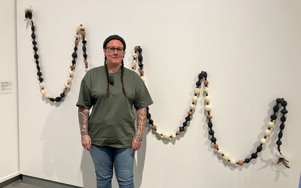 Overall winner Wellington-based artist Stevei Haukāmau standing in front of her award winning piece Kia Whakatōmuri te haere whakamua.