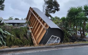 A cabin tipped on its side on Old Waipu Road.