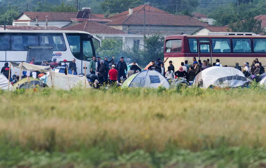 Greek police officers move refugees from one camp to another.