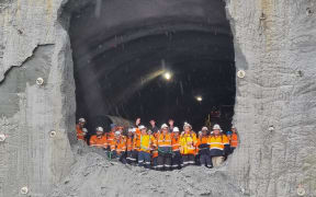 Workers peer down from the 235m tunnel after breaking through.