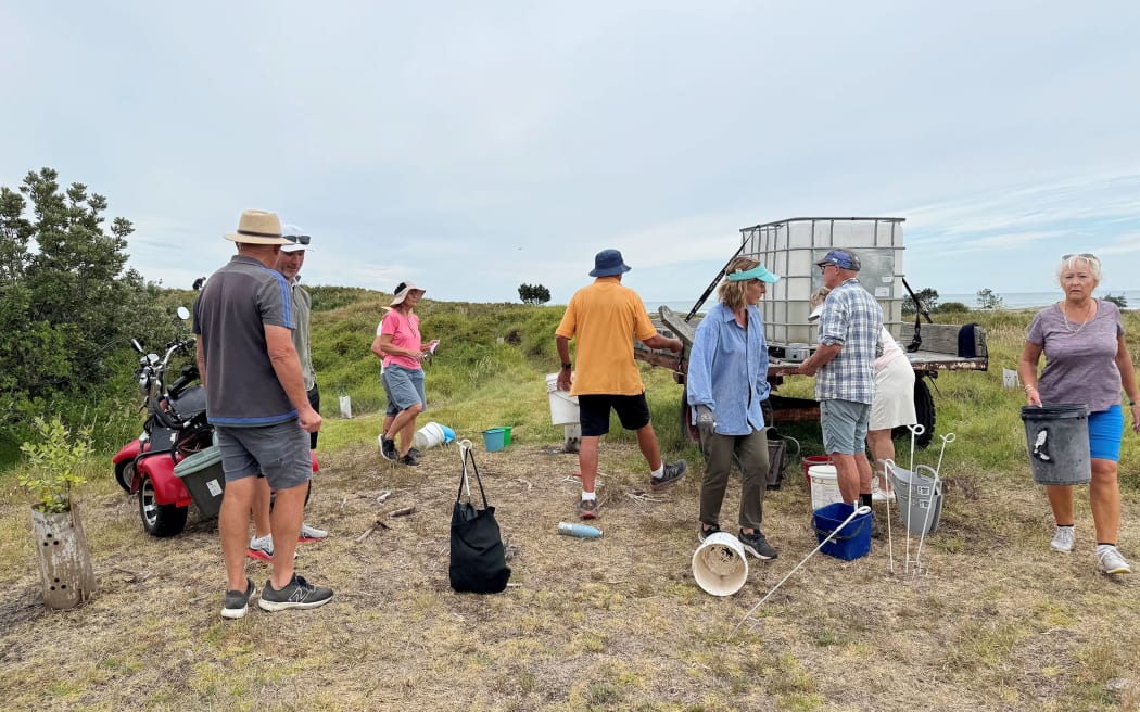 Club members take part in a watering day, carrying buckets of water to each of the new trees planted throughout the dunes.