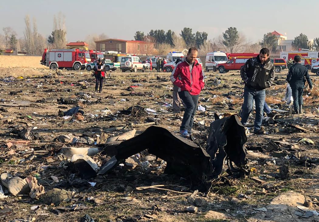 People walk near the wreckage after a Ukrainian plane carrying 176 passengers crashed near Imam Khomeini airport on January 8, 2020, killing everyone on board.