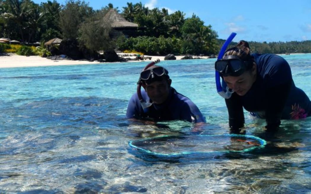 Joe Kaukura and Alice Mitchell, Aitutaki Marine Research Centre employees, helping put clams back in the lagoon in front of Pacific Resort Aitutaki.