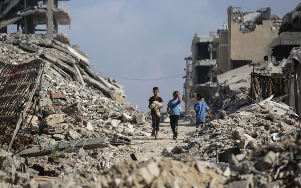 Palestinian boys make their way through the rubble of destroyed buildings in the Al-Shatee refugee camp, east of Gaza City, on November 8, 2025. Despite some progress in delivering food to Gazans, the territory, ravaged by war and wracked by hunger, remains in urgent need of humanitarian assistance, a UN spokesperson said on November 7. A ceasefire between Israel and Hamas came into effect on October 10, after both sides agreed to a US-brokered 20-point peace plan.